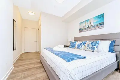 a bedroom with a large white bed with blue pillows at Condo Unit with Stunning Views & Amenities in Kitchener