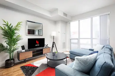 a living room with a blue couch and a tv at Perfect Condo Sleeps 4 Across from Cn Tower! in Toronto