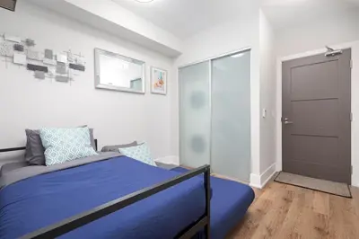 a bedroom with a blue bed and a door at Perfect Condo Sleeps 4 Across from Cn Tower! in Toronto