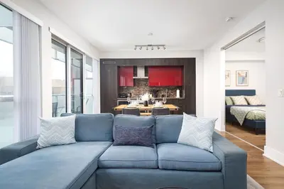 a living room with a blue couch and a kitchen at Perfect Condo Sleeps 4 Across from Cn Tower! in Toronto