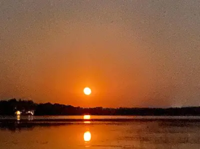 a sunset over a body of water with the sun at Sunrise net cottage in Kawartha Lakes