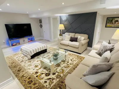 a living room with white furniture and a flat screen tv at Spacious Basement in Oakville in Oakville