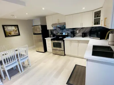 a kitchen with white cabinets and stainless steel appliances at Spacious Basement in Oakville in Oakville