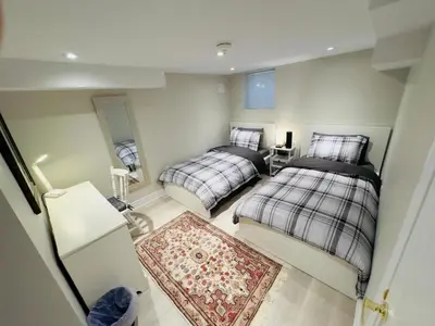 a bedroom with two beds and a rug at Spacious Basement in Oakville in Oakville