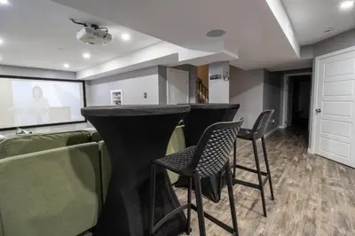 a bar in a room with chairs and a screen at The Gate Chic & Cozy Basement Retreat in Ajax in Ajax