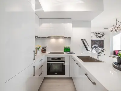 a white kitchen with white cabinets and a sink at Hazelton Suites - Yorkville - Indoor Pool & Hot Tub in Toronto
