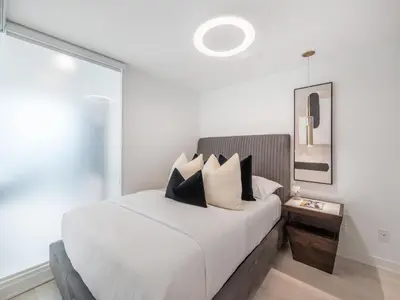 a bedroom with a white bed with black and white pillows at Hazelton Suites - Yorkville - Indoor Pool & Hot Tub in Toronto