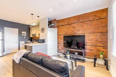 a living room with a brick wall and a couch at 1BR - Queen Bed Apartment in Hamilton's Best Neighborhood in Hamilton