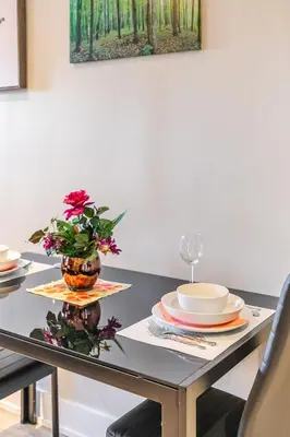 a table with plates and a vase with flowers on it at 1BR - Queen Bed Apartment in Hamilton's Best Neighborhood in Hamilton