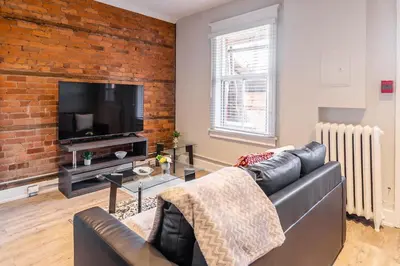 a living room with a couch and a brick wall at 1BR - Queen Bed Apartment in Hamilton's Best Neighborhood in Hamilton