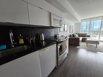 a kitchen with white appliances and a living room at Downtown City View Escape with Free Parking in Toronto