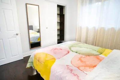 a bedroom with a bed with colorful sheets and a mirror at Stunning Vacation Home North of Toronto in Richmond Hill