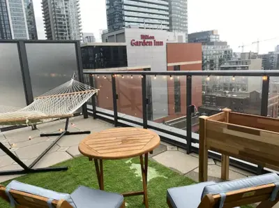 a balcony with a hammock and a table and chairs at Bright 1BR w Large Terrace - Entertainment District in Toronto