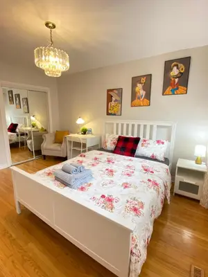 a bedroom with a white bed with a floral bedspread at Sunny House - Main Floor, Free parking, in Toronto in Toronto