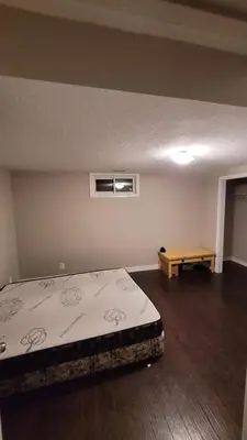 an empty room with a bed and a table at 3 Room Set for Up to 8 people- 10 minutes from Kitchener Airport, Walking to Transit in Kitchener