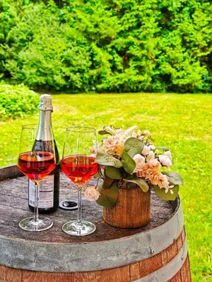 two glasses of wine and a bottle on a barrel at Walk to Lake - Old Town Retreat in Niagara on the Lake