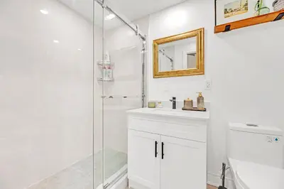 a white bathroom with a shower and a sink at Walk to Lake - Old Town Retreat in Niagara on the Lake