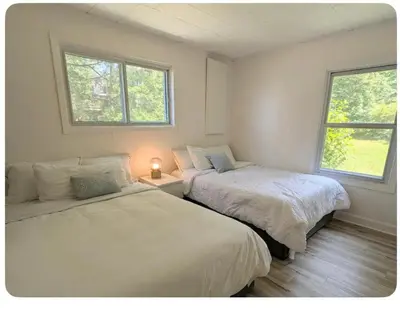 two beds in a room with two windows at Cottage on Private Beach in Penetanguishene