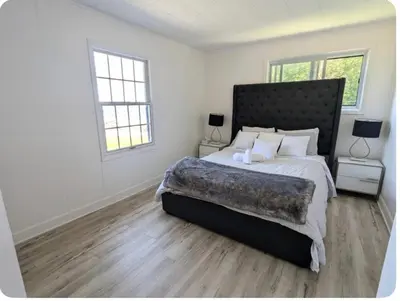 a bedroom with a large bed and two windows at Cottage on Private Beach in Penetanguishene