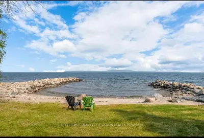 two people sitting in chairs on the beach at Cottage on Private Beach in Penetanguishene