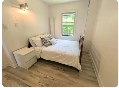 a small bedroom with a bed and a window at Cottage on Private Beach in Penetanguishene