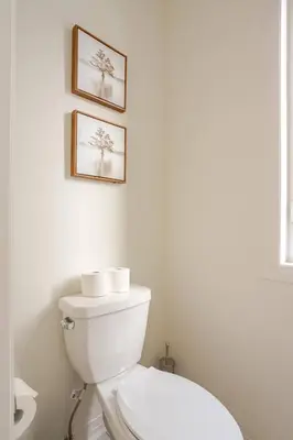 a bathroom with a toilet and two pictures on the wall at Stylish 4br Fast Wifi Sleeps 10 in Barrie