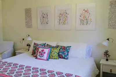 a bedroom with a white bed with colorful pillows at Birdsong Bungalow in Port Dover