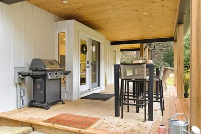 a screened in porch with a grill and chairs at Redwood Suite in Niagara on the Lake