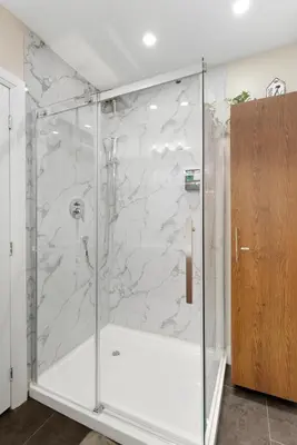 a shower with a glass door in a bathroom at Spruce Suite in Niagara on the Lake