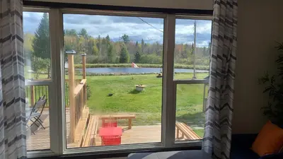 a window with a view of a deck and a lake at Peaceful and Heavenly Private Water Front Cottage on 100 Acres of Scenic Beauty- Trent Lakes in Kinmount