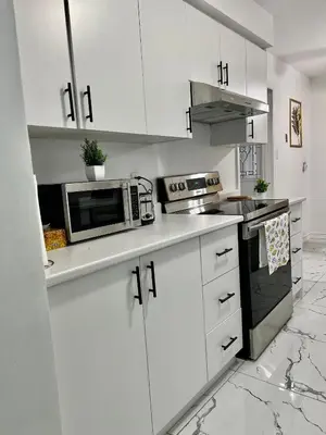 a white kitchen with white cabinets and a microwave at Private Room Near Airport K5 in Mississauga
