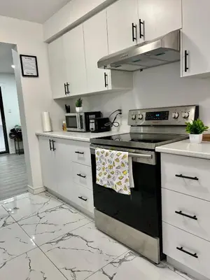 a kitchen with white cabinets and a stove top oven at Private Room Near Airport K4 in Mississauga
