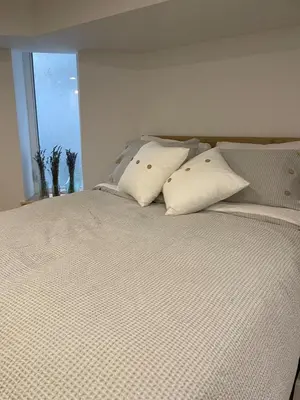 a bed with white pillows and a window in a room at Lower level newly renovated studio apartment in central downtown location in Toronto