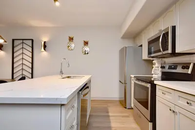 a kitchen with white countertops and a stainless steel refrigerator at Stunning Condo with Access to Pool in Shanty Bay