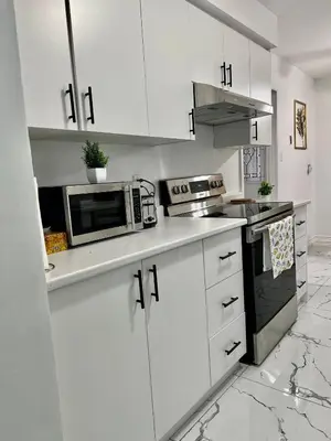 a white kitchen with white cabinets and a microwave at K1 Private Bathroom Queen Bed Room in Mississauga