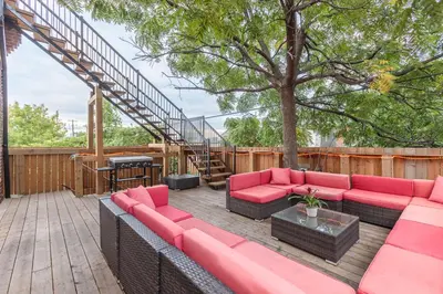 a patio with a red couch and a tree at Renovated Church Hamilton! Guest Suite in Hamilton