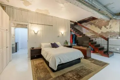 a bedroom with a large bed and a staircase at Renovated Church Hamilton! Guest Suite in Hamilton