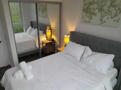 a bedroom with a large white bed and a mirror at Nature trail view with cozy patio and firetable in Innisfil