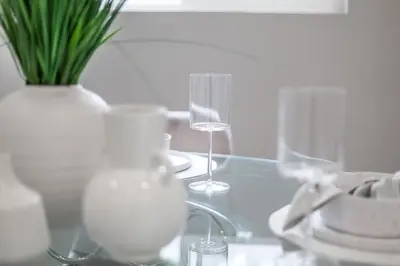 a glass table with two wine glasses and a vase at Lake House By Lis in Innisfil