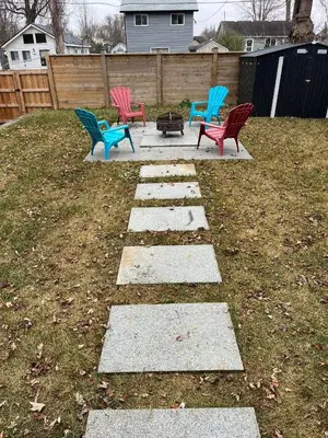 four colorful chairs sitting on a stone walkway in a yard at Lake House By Lis in Innisfil