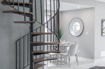 a spiral staircase in a dining room with a table at Lake House By Lis in Innisfil