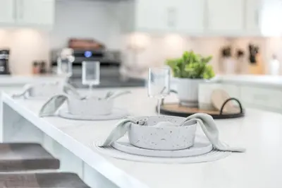 a white kitchen counter with two plates and wine glasses at Lake House By Lis in Innisfil