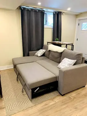 a couch in a living room with black curtains at Cozy 1 bedroom basement apartment 14 days minimum in Fonthill