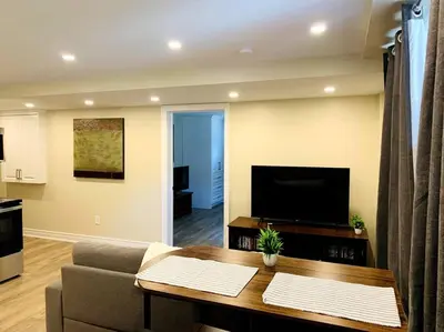 a living room with a couch and a television at Cozy 1 bedroom basement apartment 14 days minimum in Fonthill