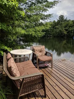 two wicker chairs and a table on a wooden deck at Summit Cottage on Kawagama Lake in Dorset