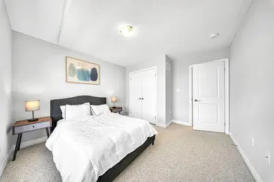 a white bedroom with a bed and two white doors at Lavish Home on Hamilton Mountain in Hamilton