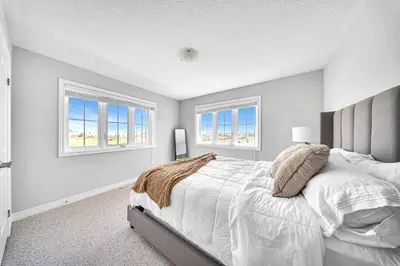 a white bedroom with a large bed and two windows at Lavish Home on Hamilton Mountain in Hamilton