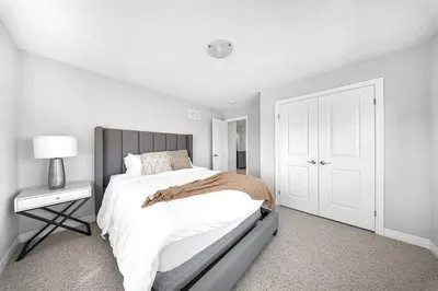 a white bedroom with a bed and a lamp and a door at Lavish Home on Hamilton Mountain in Hamilton