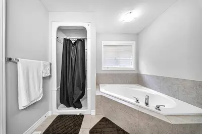 a white bathroom with a tub and a window at Lavish Home on Hamilton Mountain in Hamilton