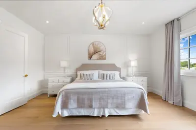 a white bedroom with a bed and a chandelier at Luxury Home - 5 min from airport, 15 to downtown in Toronto